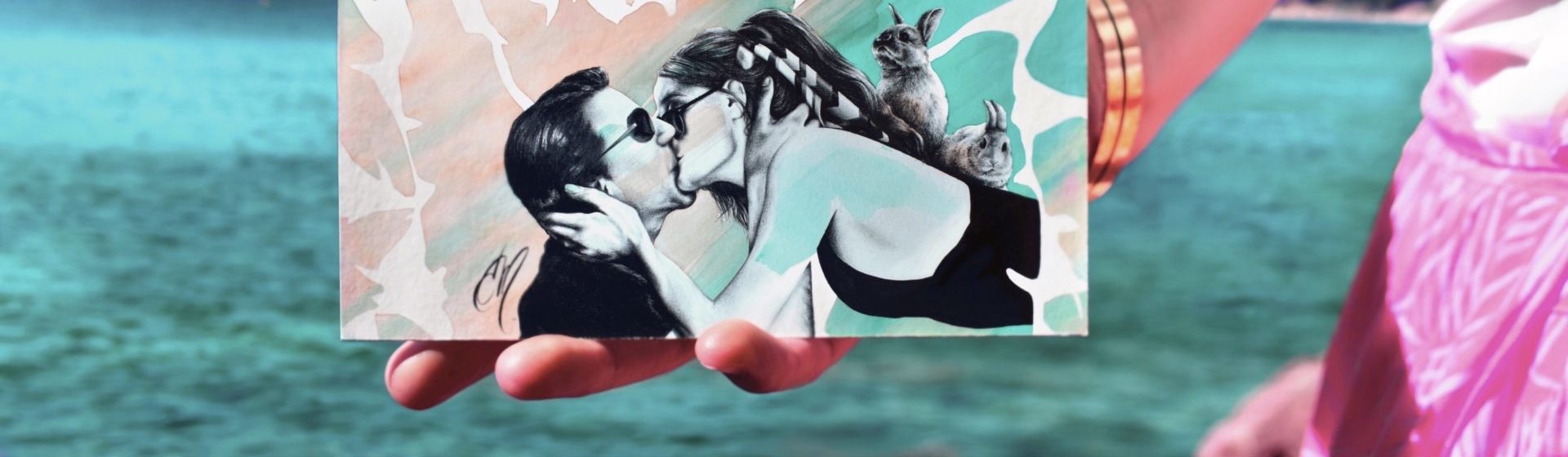 présentation d'une carte postale représentant un couple s'embrassant et deux lapins, paysage au bord de la mer, couleurs turquoises et rosées